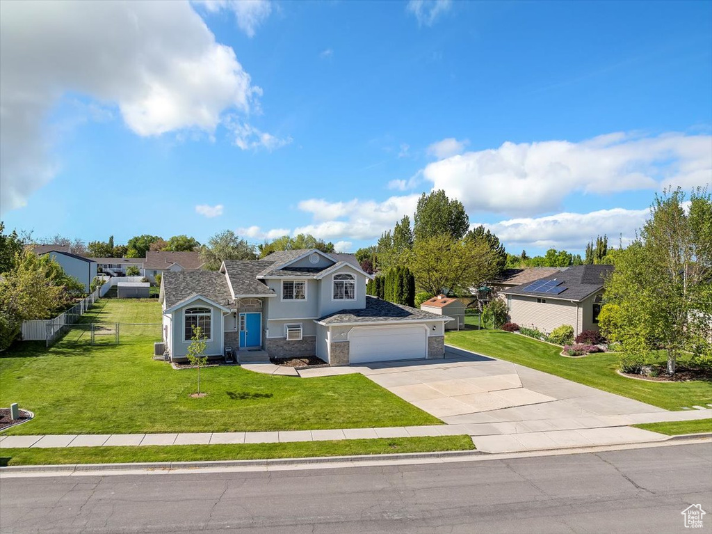 Traditional-style house with fence, stone siding, stucco siding, a front yard, and driveway