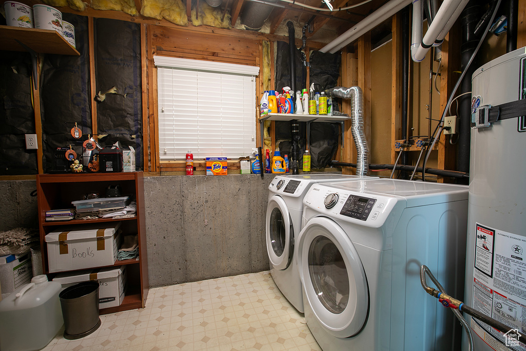 Clothes washing area featuring separate washer and dryer, laundry area, strapped water heater, and light floors