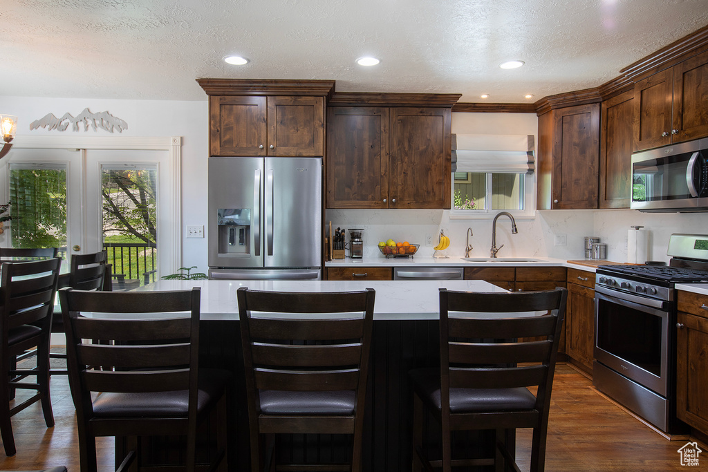 Kitchen with light countertops, stainless steel appliances, a sink, and dark wood-type flooring