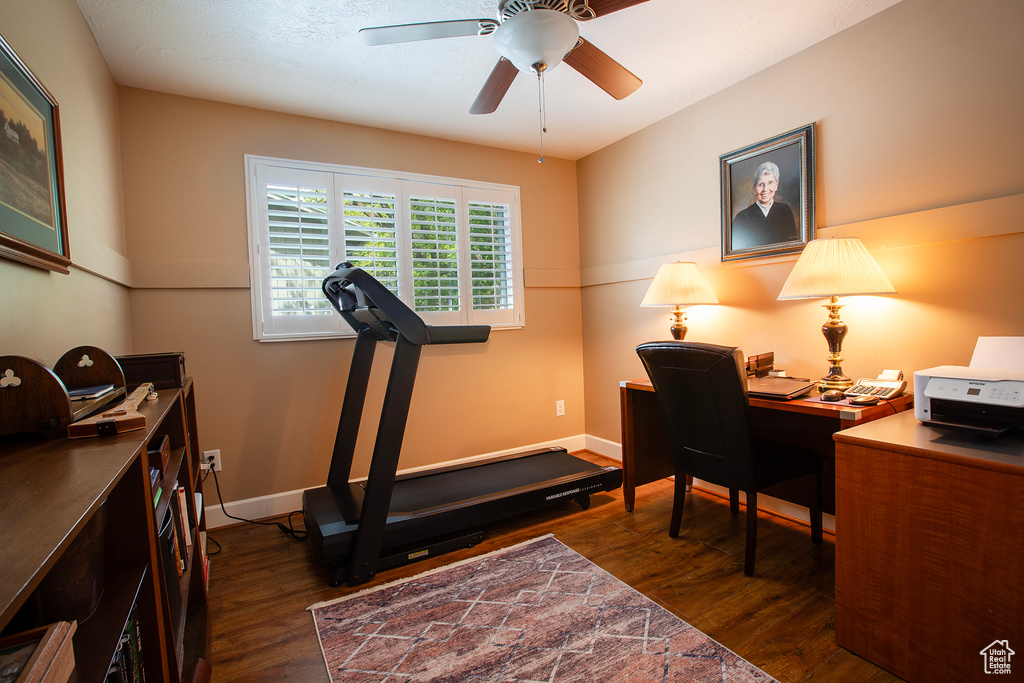 Home office with baseboards, a ceiling fan, and dark wood-style floors
