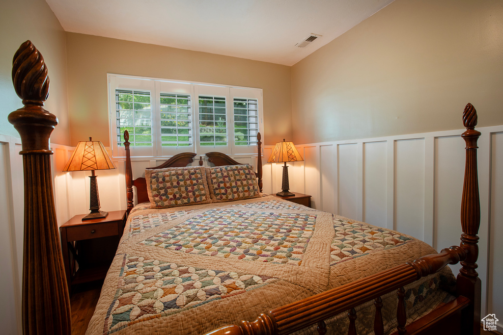 Bedroom with a decorative wall, visible vents, and a wainscoted wall