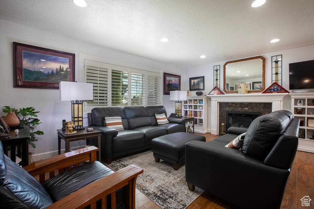 Living room with a high end fireplace, baseboards, recessed lighting, and wood finished floors