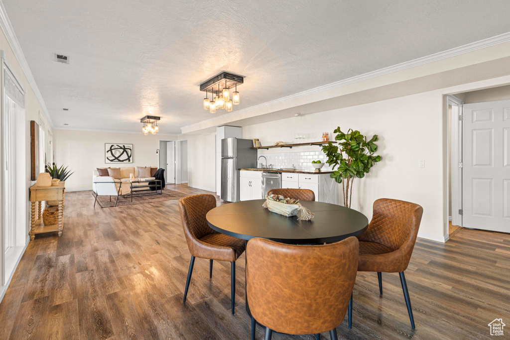 Dining room with visible vents, crown molding, baseboards, an inviting chandelier, and dark wood-type flooring