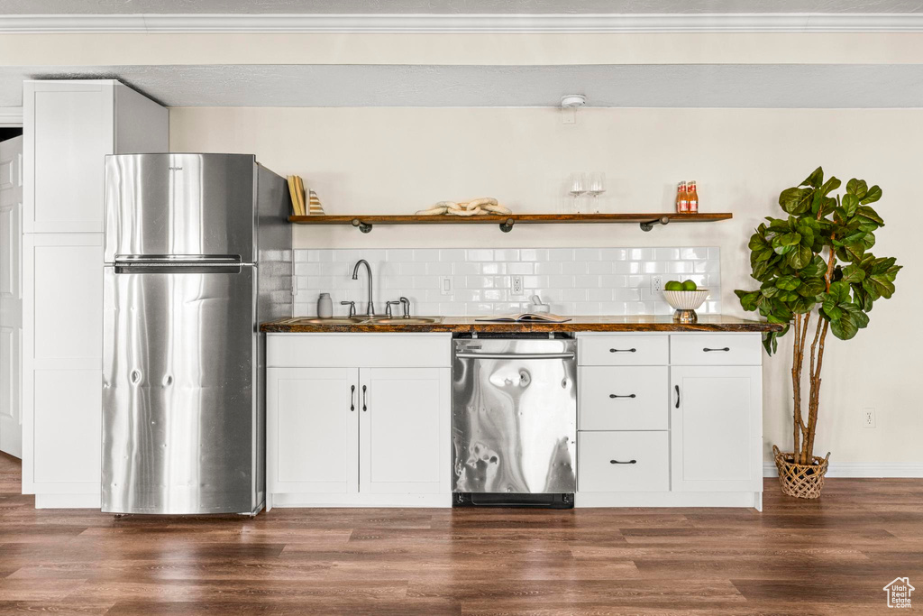 Kitchen featuring open shelves, decorative backsplash, butcher block countertops, a sink, and stainless steel appliances