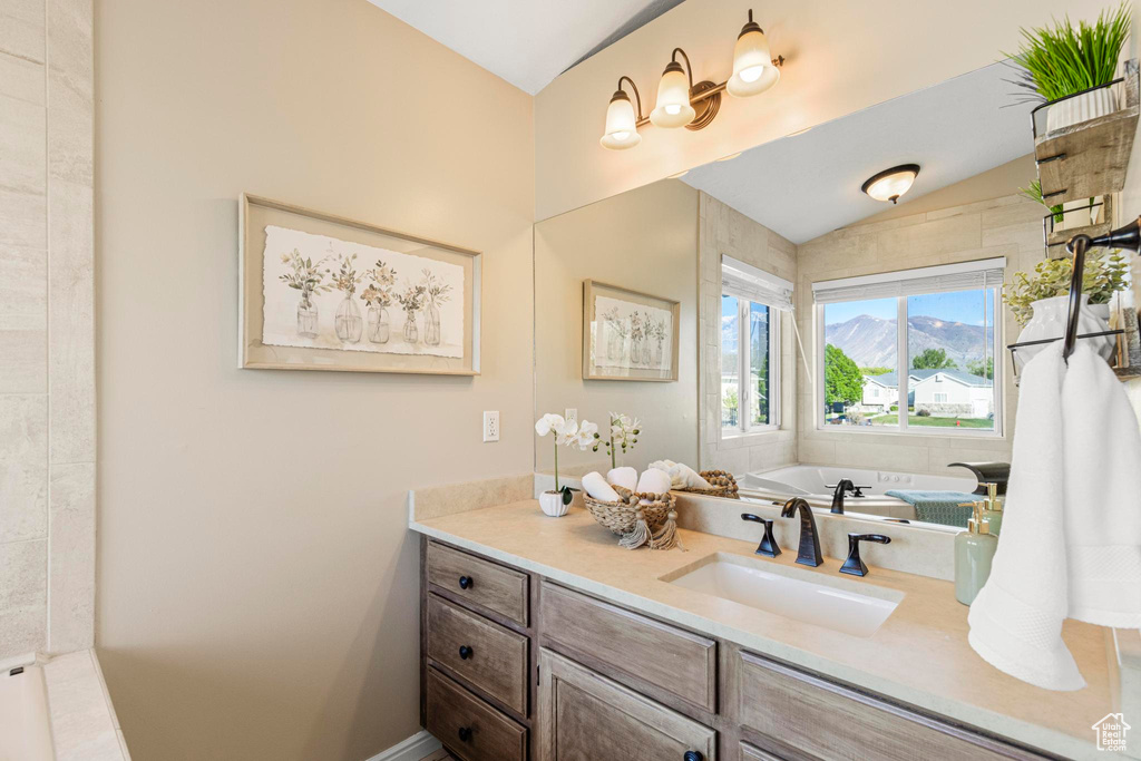 Bathroom with a bathing tub, vaulted ceiling, and vanity