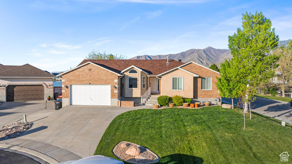 Ranch-style house with a garage, a front lawn, stucco siding, concrete driveway, and a mountain view
