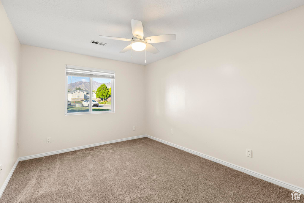 Carpeted empty room featuring visible vents, baseboards, and ceiling fan