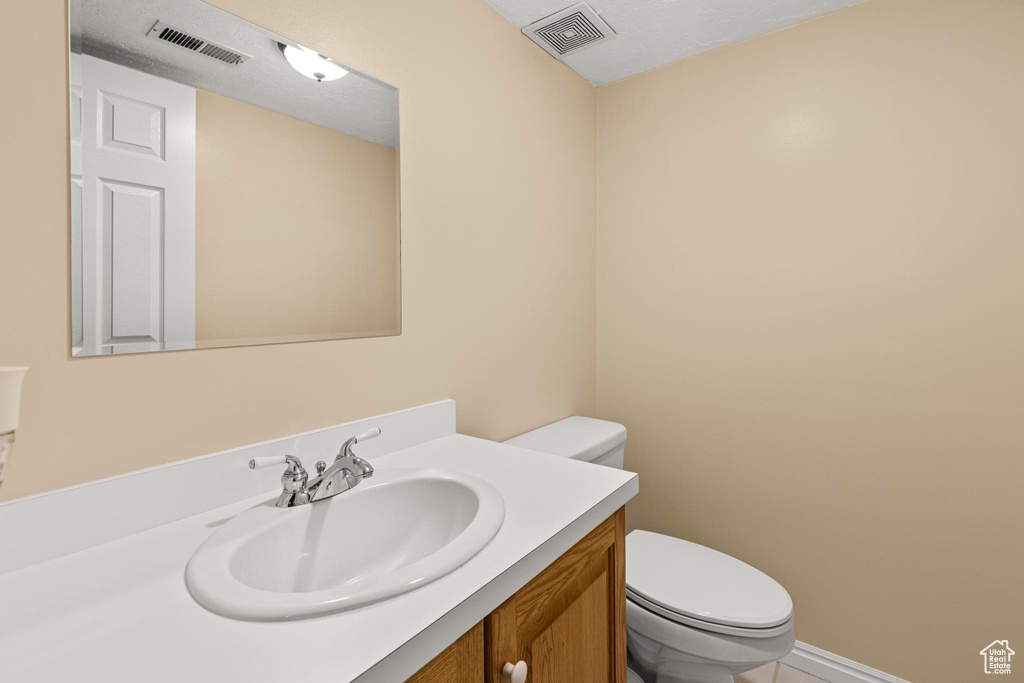 Half bath featuring vanity, toilet, and visible vents