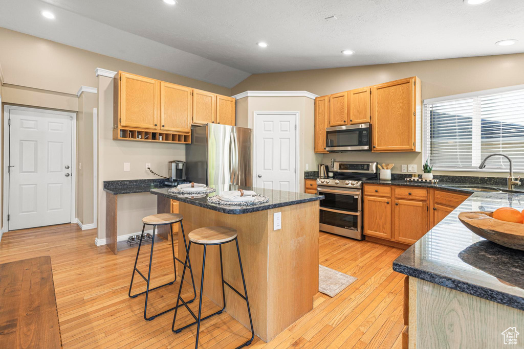 Kitchen featuring a sink, light wood-style flooring, a kitchen island, and stainless steel appliances