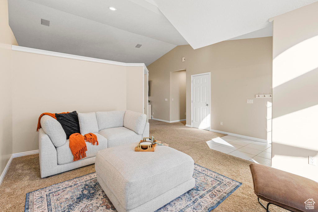 Living area featuring baseboards, light colored carpet, light tile patterned floors, and vaulted ceiling