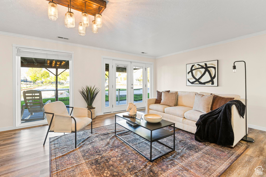 Living room with plenty of natural light, ornamental molding, and wood finished floors