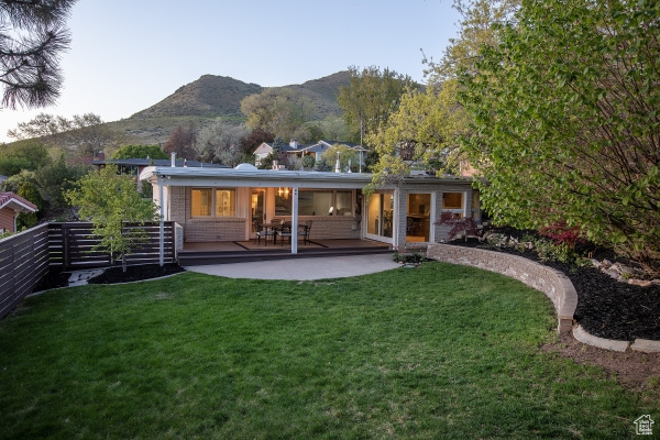Rear view of property with a patio area, a mountain view, a yard, and fence