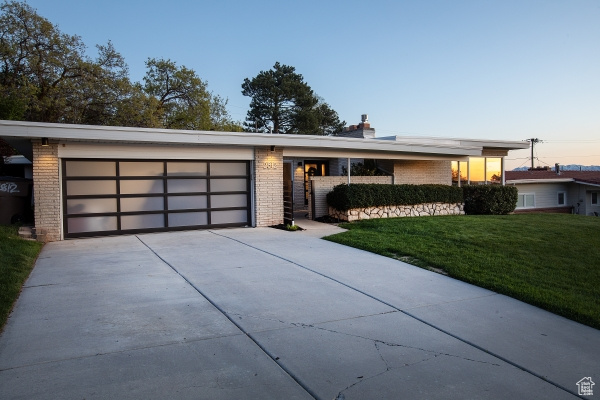 Contemporary home with concrete driveway, a front yard, and brick siding