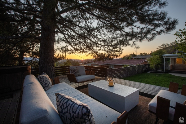 Patio terrace at dusk featuring an outdoor living space, fence, a yard, and a deck