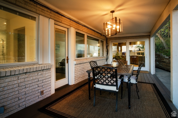 Sunroom with an inviting chandelier, outdoor dining space, and brick wall