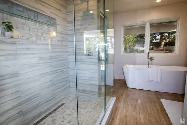 Bathroom featuring a freestanding bath, a stall shower, recessed lighting, and wood finished floors