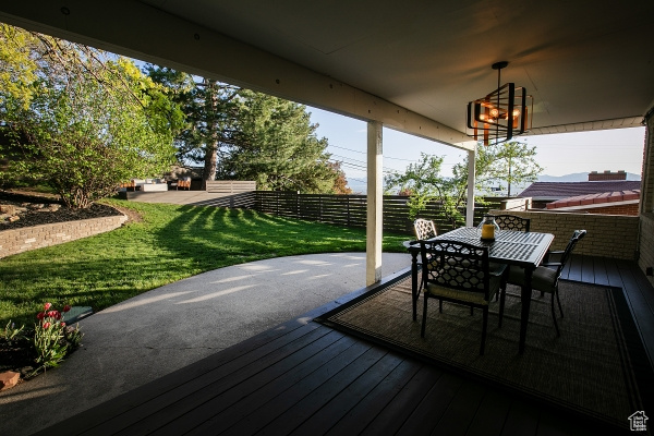 Deck with a lawn, fence, and outdoor dining space