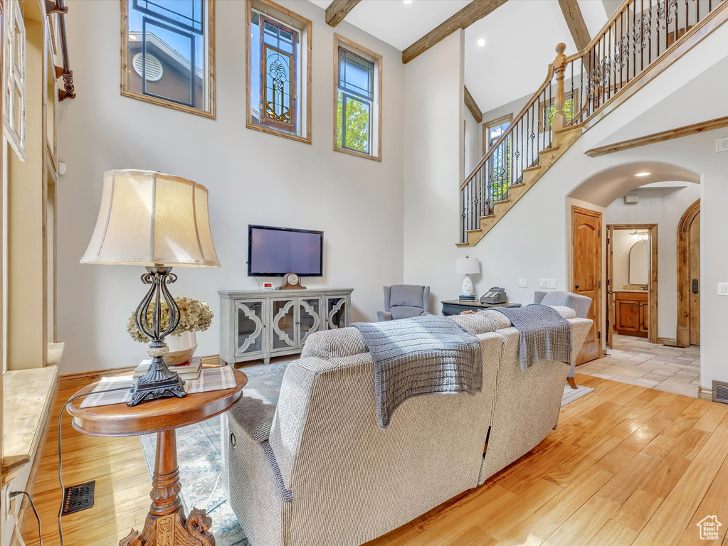 Living room featuring visible vents, a towering ceiling, arched walkways, wood finished floors, and stairway