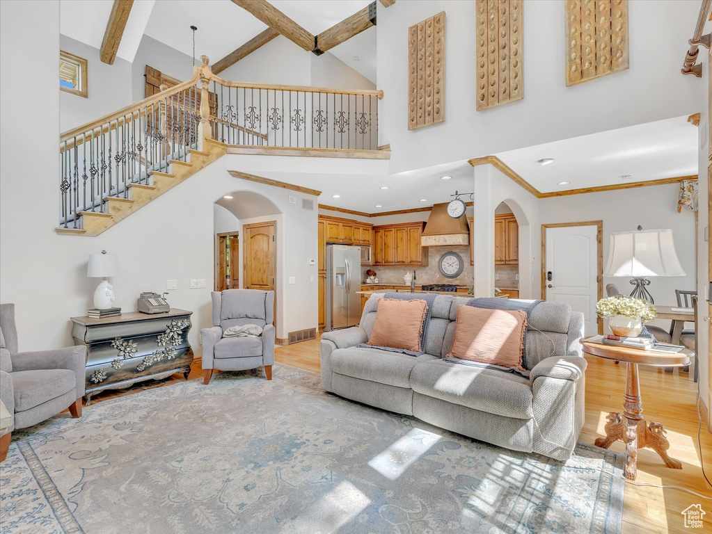 Living area featuring stairway, arched walkways, high vaulted ceiling, and light wood-style flooring