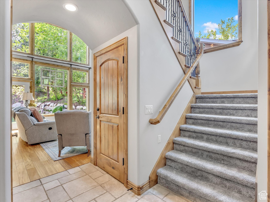 Stairway with baseboards, lofted ceiling, and a wealth of natural light
