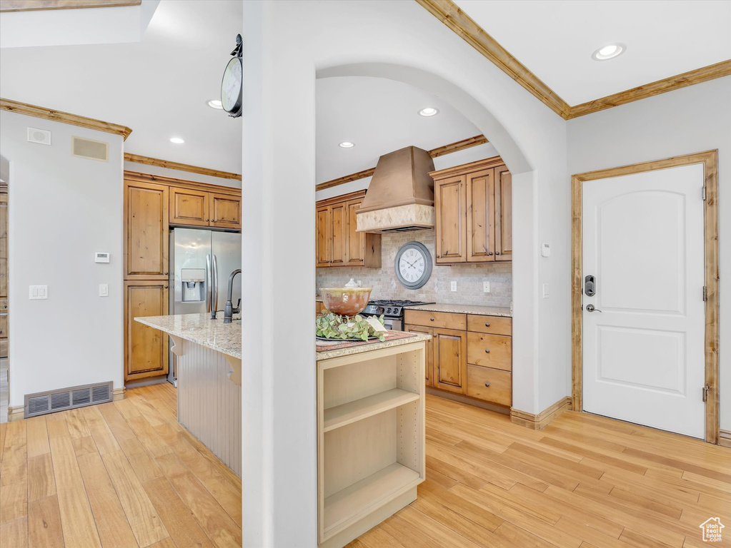 Kitchen with visible vents, crown molding, custom exhaust hood, an island with sink, and stainless steel appliances