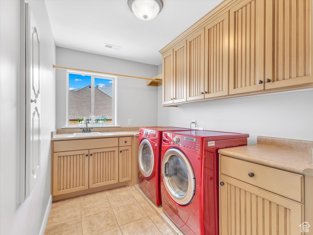 Laundry area featuring independent washer and dryer, visible vents, cabinet space, a sink, and light tile patterned floors