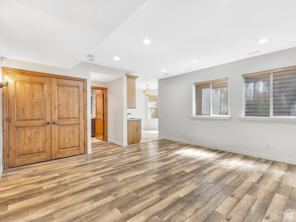 Unfurnished living room featuring light wood-style floors, baseboards, recessed lighting, and visible vents