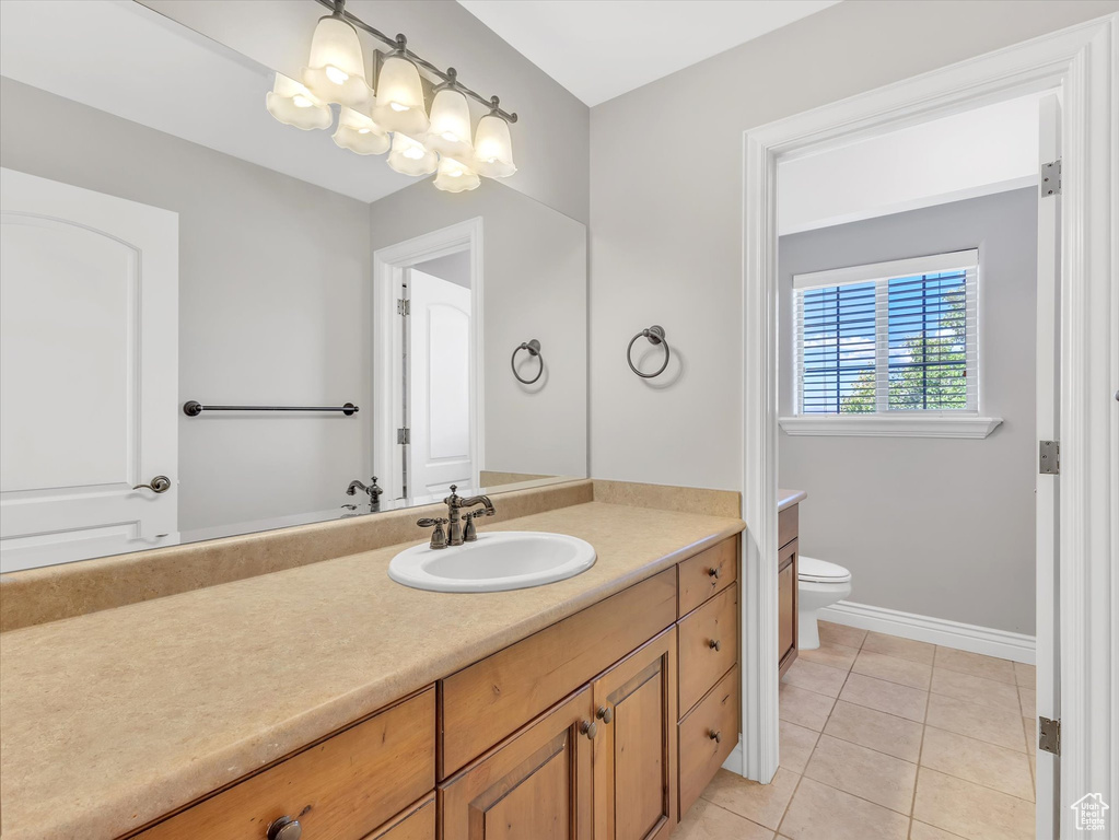 Bathroom featuring toilet, baseboards, tile patterned flooring, and vanity