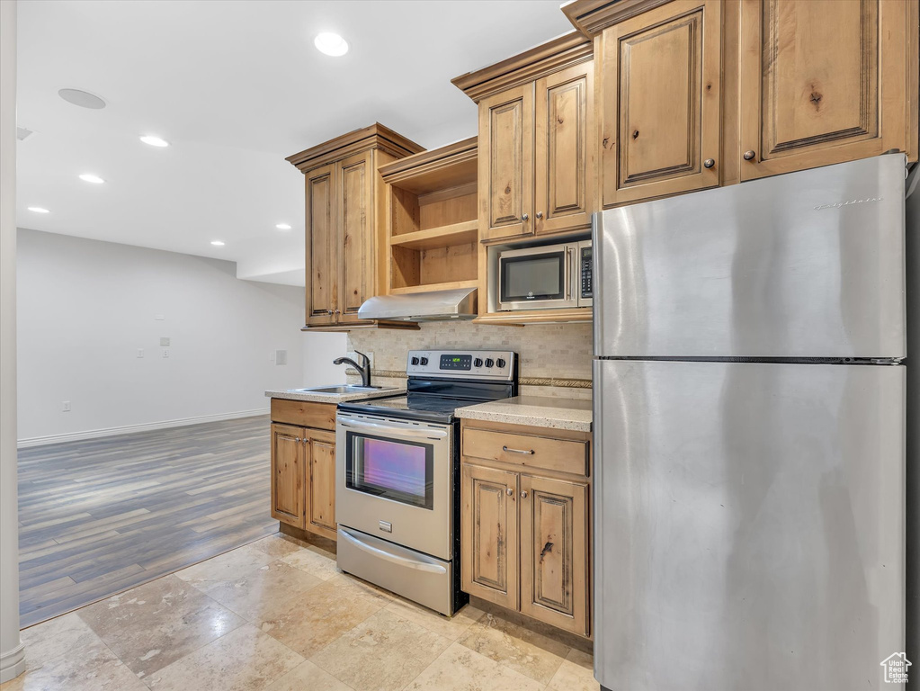 Kitchen with open shelves, a sink, backsplash, exhaust hood, and stainless steel appliances
