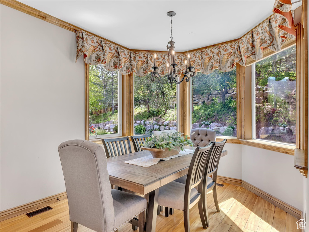 Dining room with an inviting chandelier, baseboards, light wood-style flooring, and visible vents