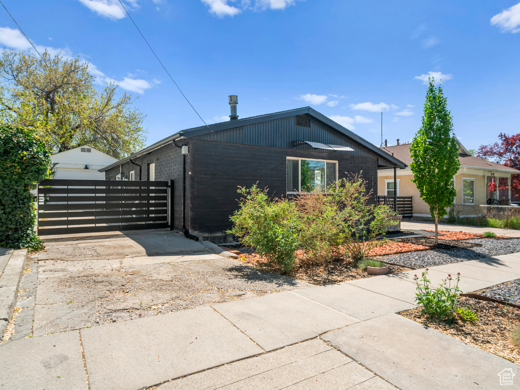 View of home's exterior with fence, a gate, concrete driveway, and brick siding