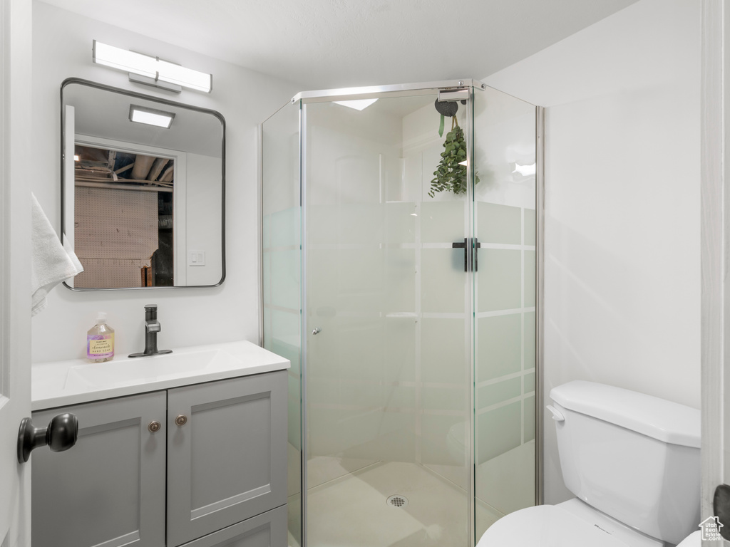 Bathroom with toilet, a shower stall, and vanity