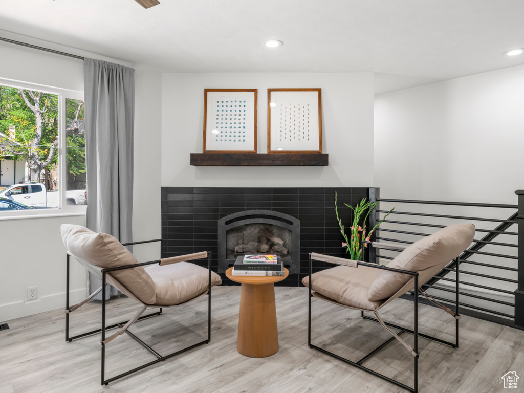 Living area with recessed lighting, baseboards, a tiled fireplace, and light wood-type flooring