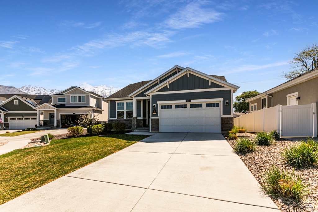 Craftsman house with a garage, a front lawn, fence, board and batten siding, and concrete driveway
