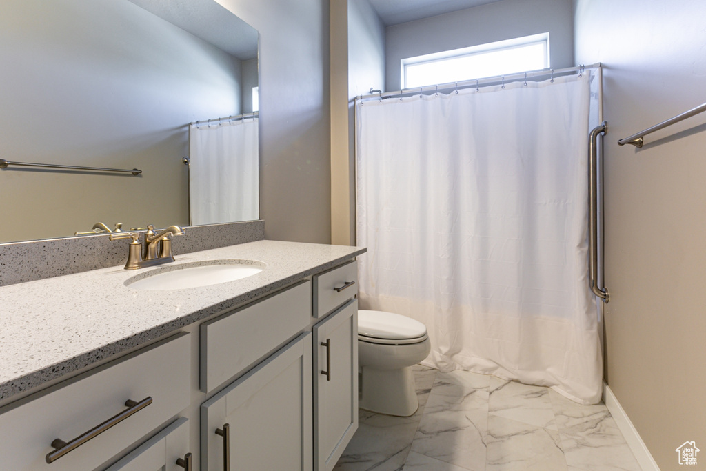Bathroom featuring vanity, a shower with shower curtain, toilet, and marble finish floor