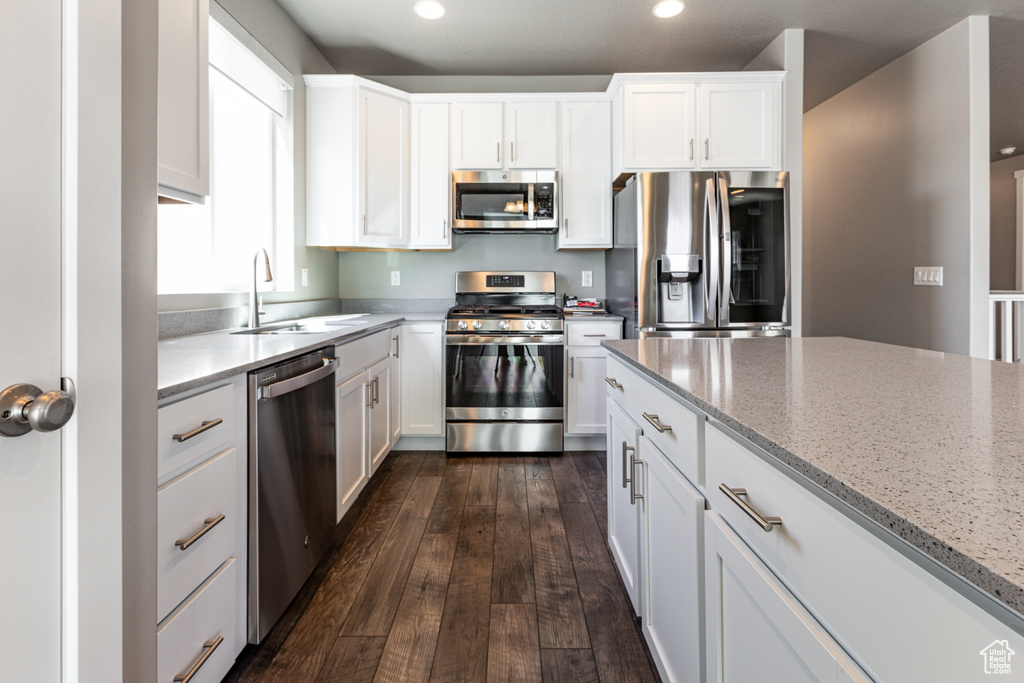 Kitchen with recessed lighting, white cabinetry, a sink, dark wood finished floors, and stainless steel appliances
