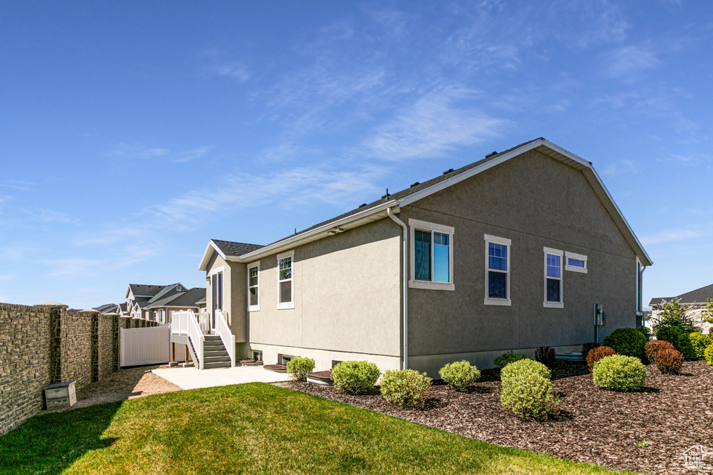 View of property exterior featuring a yard, fence, a patio area, and stucco siding