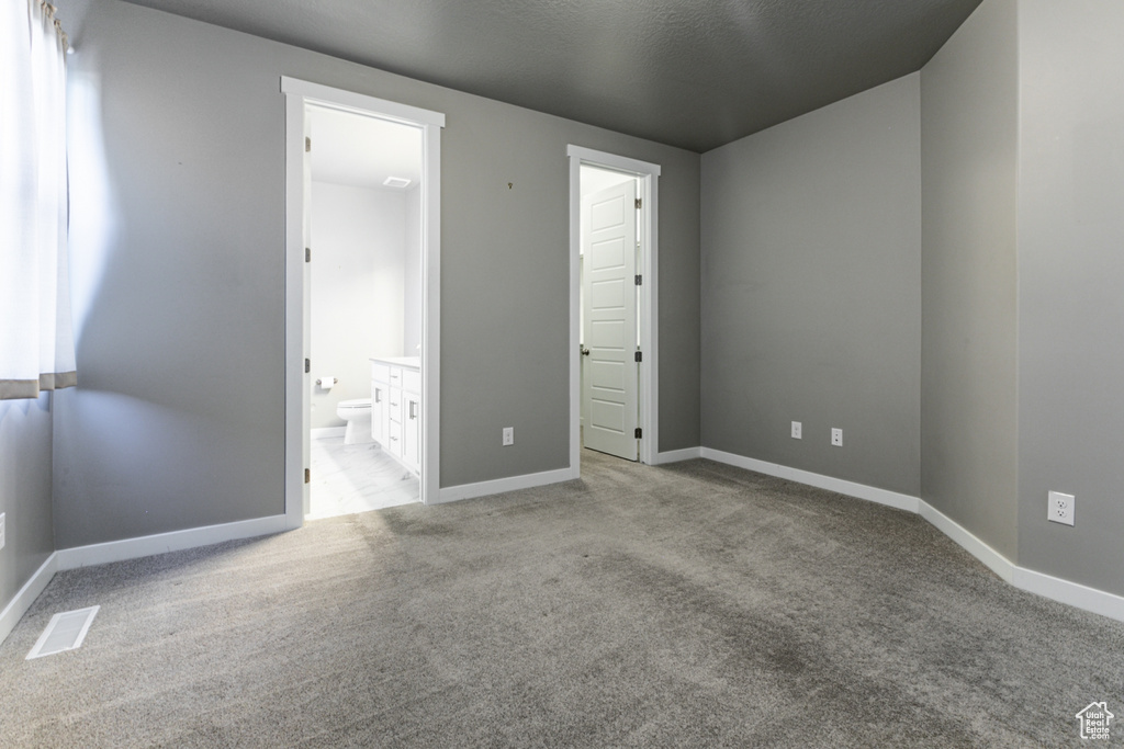 Unfurnished bedroom featuring baseboards, carpet flooring, and ensuite bath