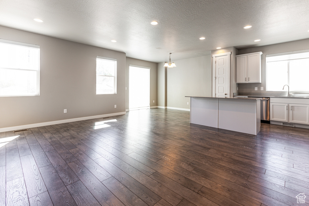 Kitchen featuring a kitchen island, open floor plan, dark wood-style floors, recessed lighting, and a sink