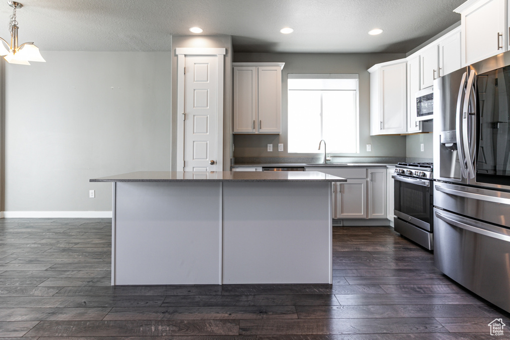 Kitchen featuring a center island, recessed lighting, dark wood-type flooring, a sink, and stainless steel appliances