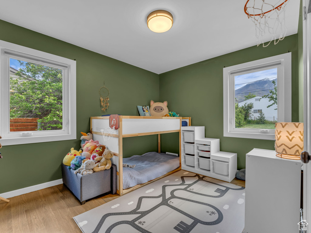 Bedroom with baseboards, multiple windows, and wood finished floors