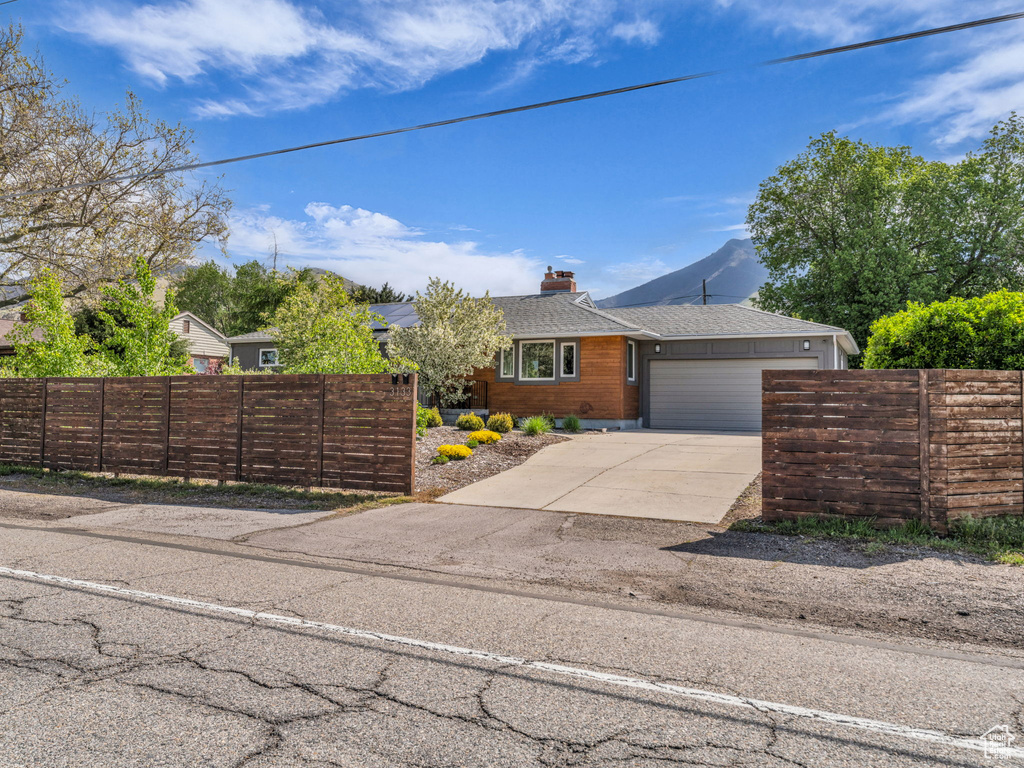 Ranch-style house with fence private yard, an attached garage, driveway, and a chimney