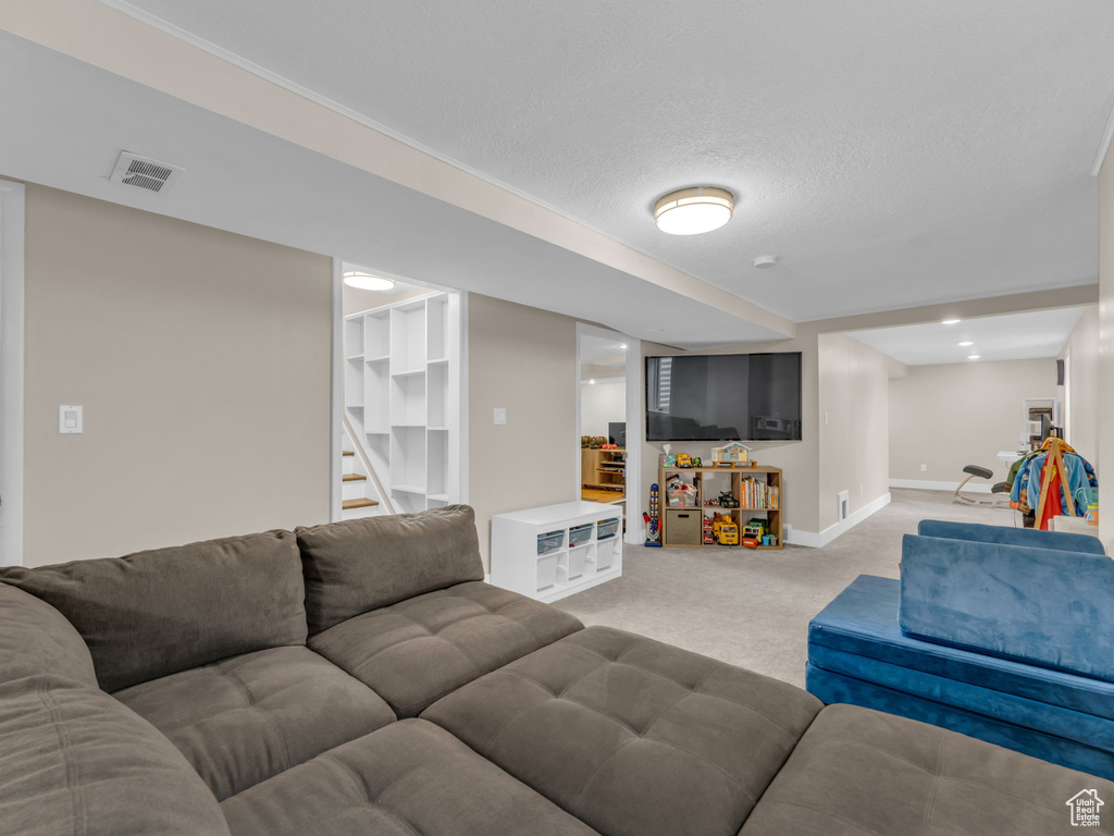 Living room featuring stairway, baseboards, light carpet, and visible vents