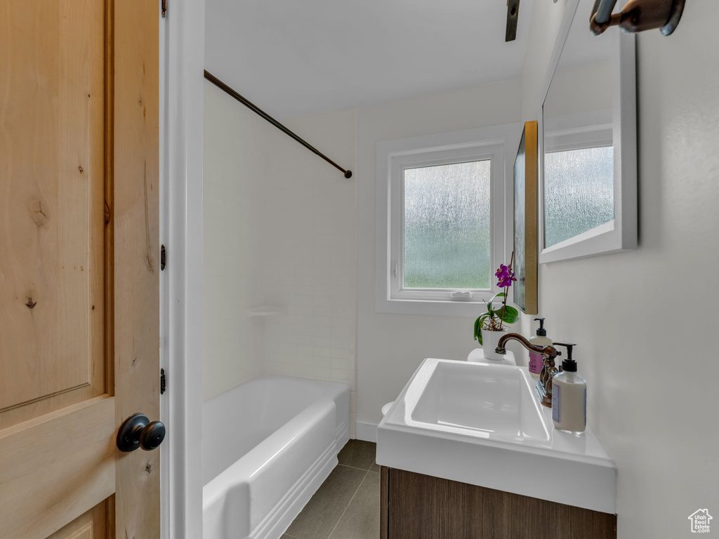 Bathroom with tile patterned floors, washtub / shower combination, and vanity