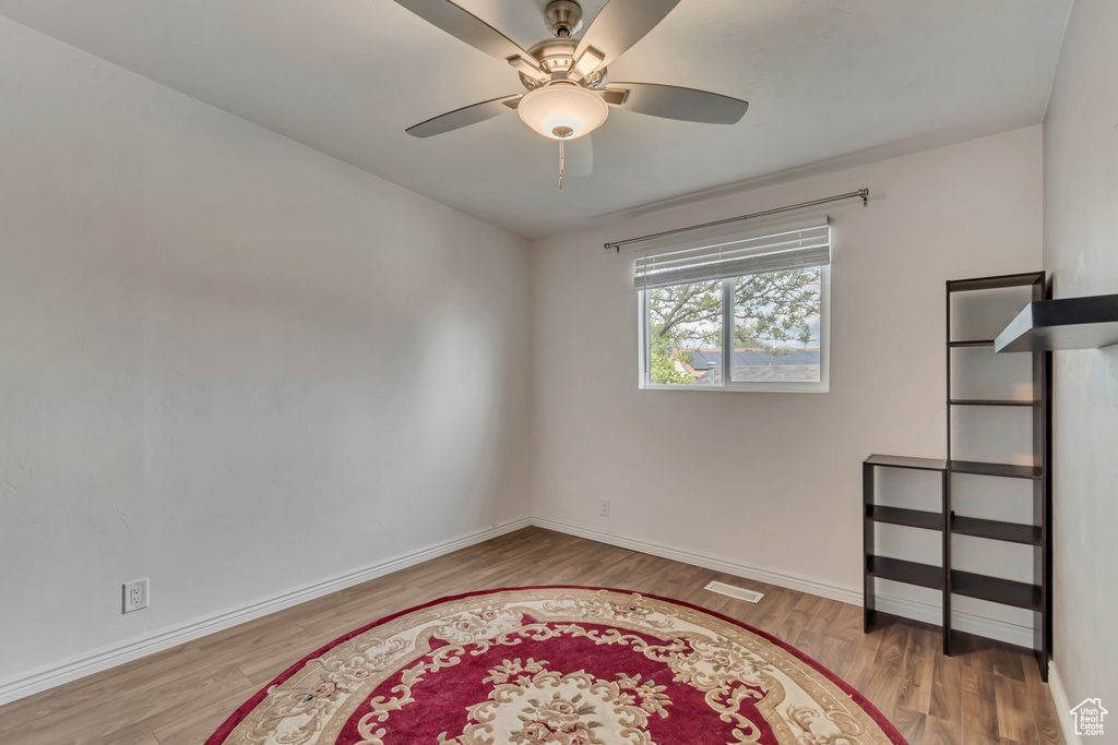 Spare room featuring a ceiling fan, baseboards, and wood finished floors