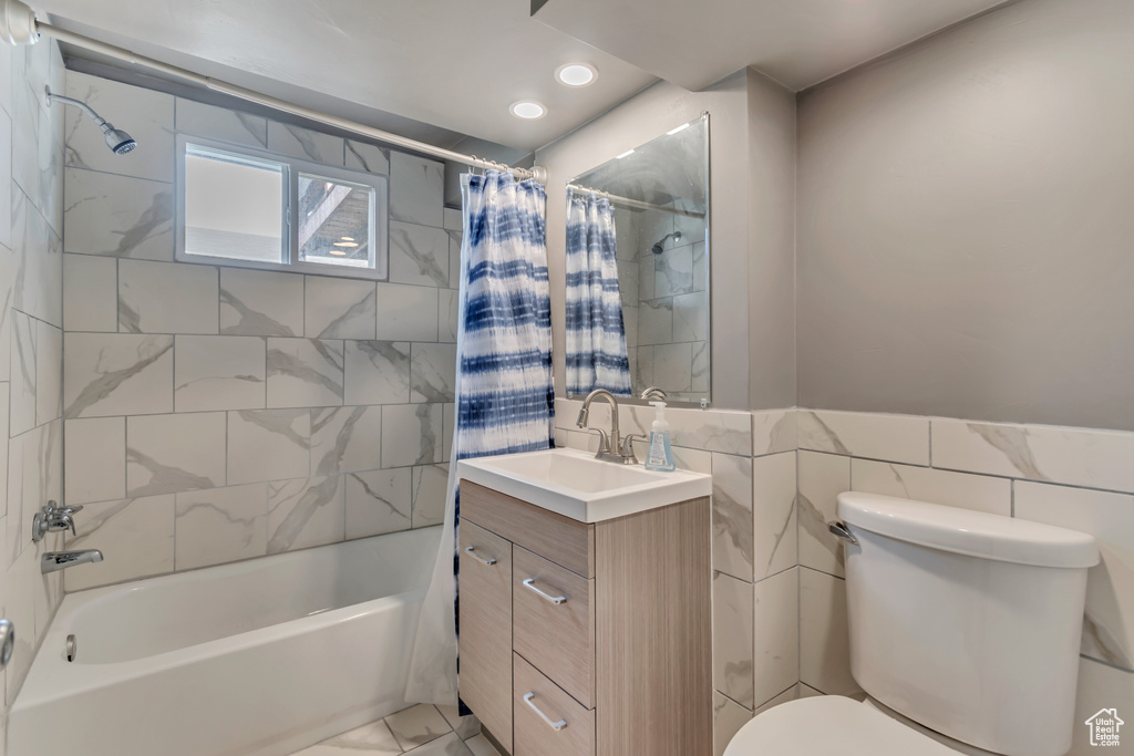 Full bath with shower / bath combo, vanity, toilet, recessed lighting, and tile walls