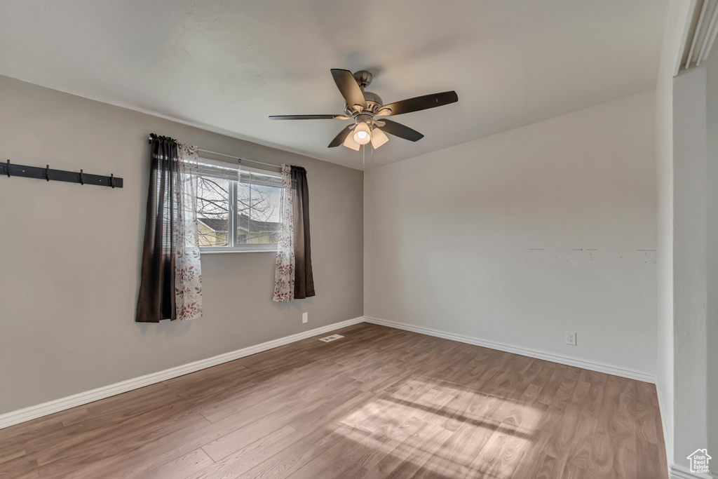 Unfurnished room with baseboards, a ceiling fan, wood finished floors, and visible vents