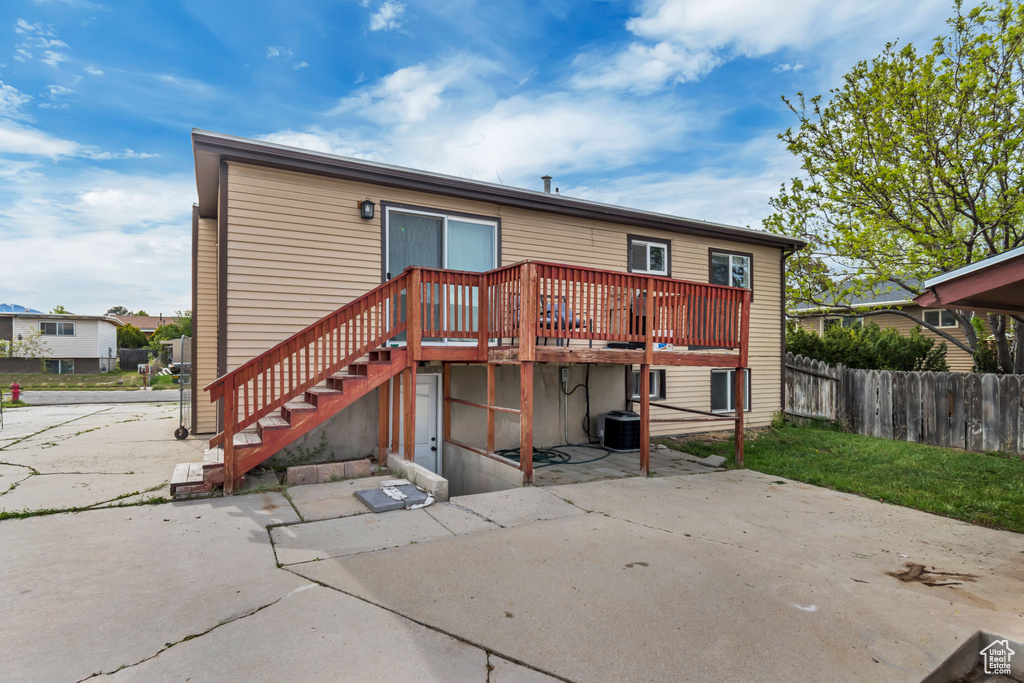 Rear view of property featuring a wooden deck, a patio area, central AC, fence, and stairs