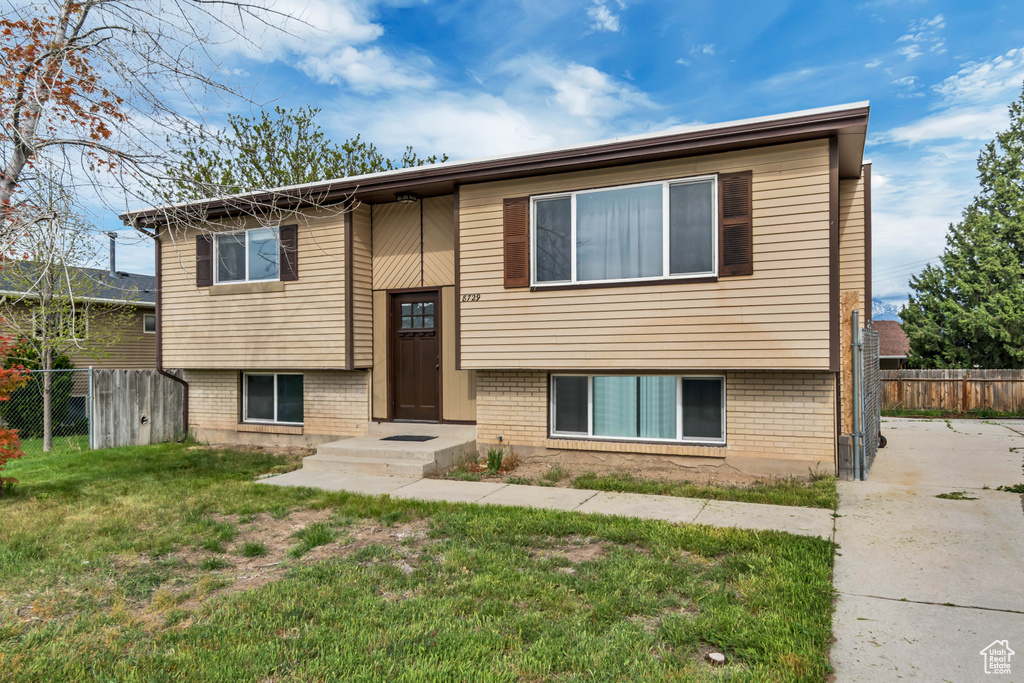 Bi-level home with brick siding, fence, and a front lawn