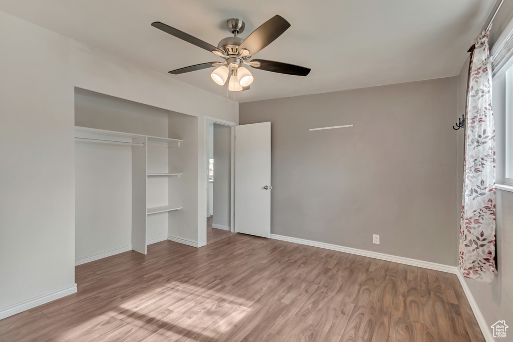 Unfurnished bedroom featuring a ceiling fan, baseboards, wood finished floors, and a closet